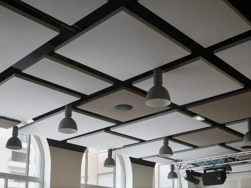 A black coffered ceiling grid with pendant lights over an open commercial floor