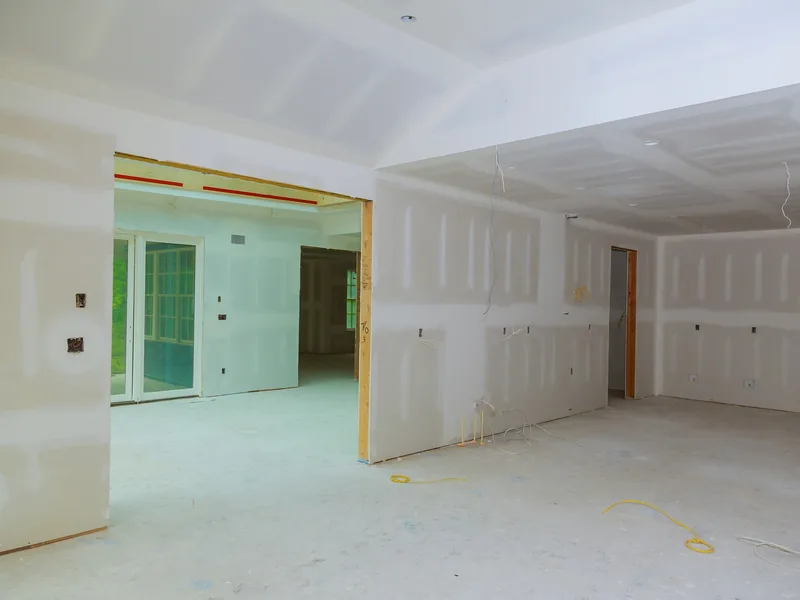 A long boarded corridor with openings cut for doors and services, one unit of a multi-unit job