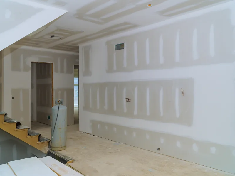 A corridor boarded out in drywall with panels leaning against the wall ready to hang