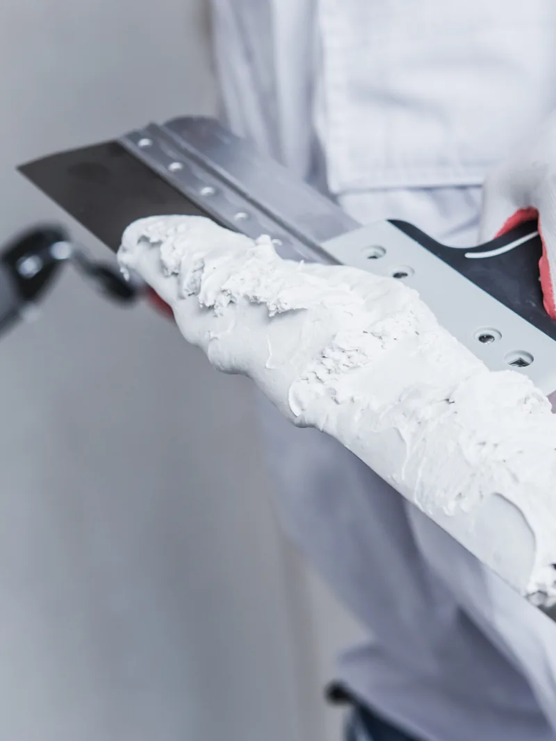 A broad knife held up loaded with compound for feathering out over a bead