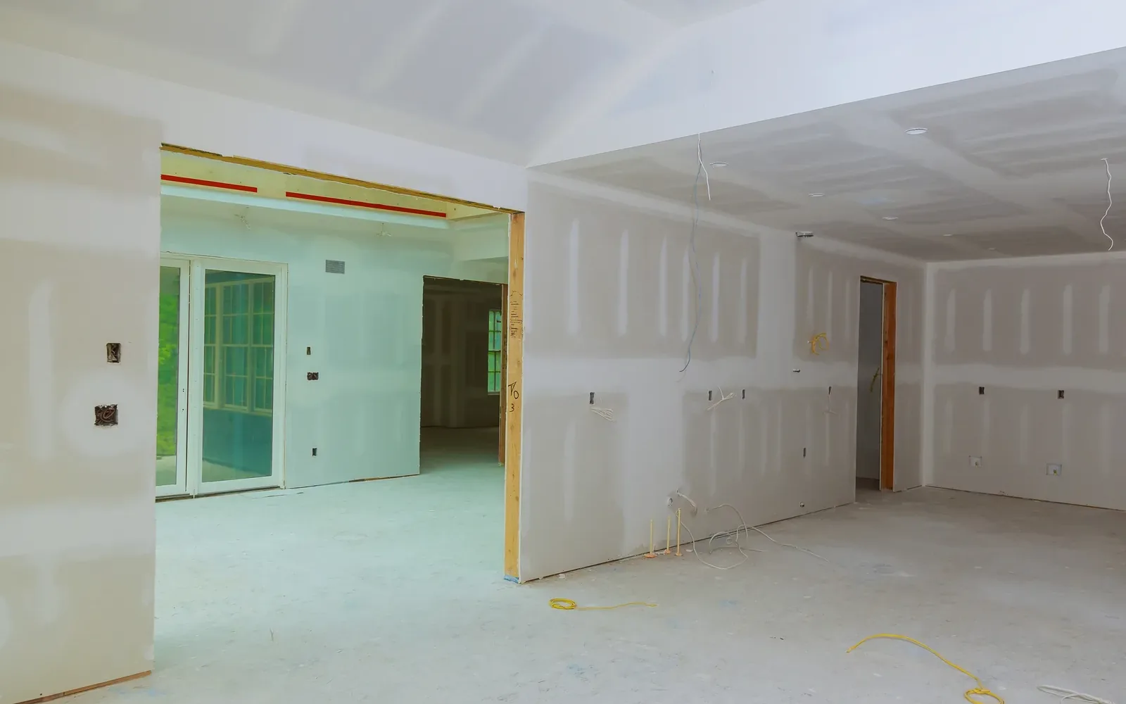 A long drywalled corridor with openings cut for doors and services