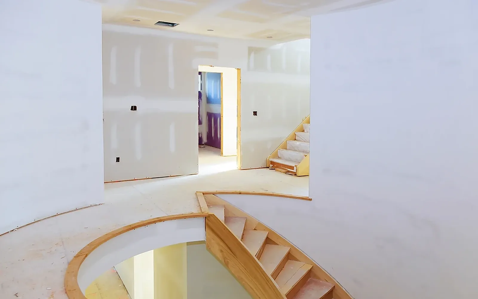 A custom curved drywall wall following a staircase up to a landing