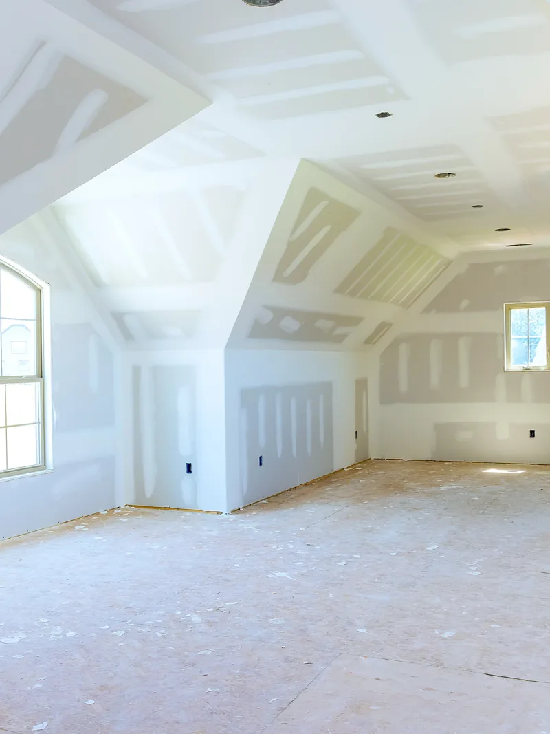 A dormer room boarded and taped throughout, with a vaulted and coffered ceiling