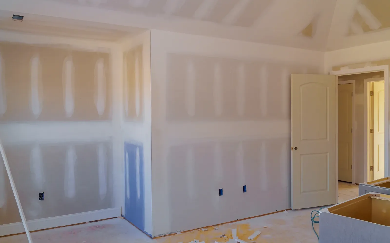A part-renovated room with taped drywall walls and a cabinet run going back in