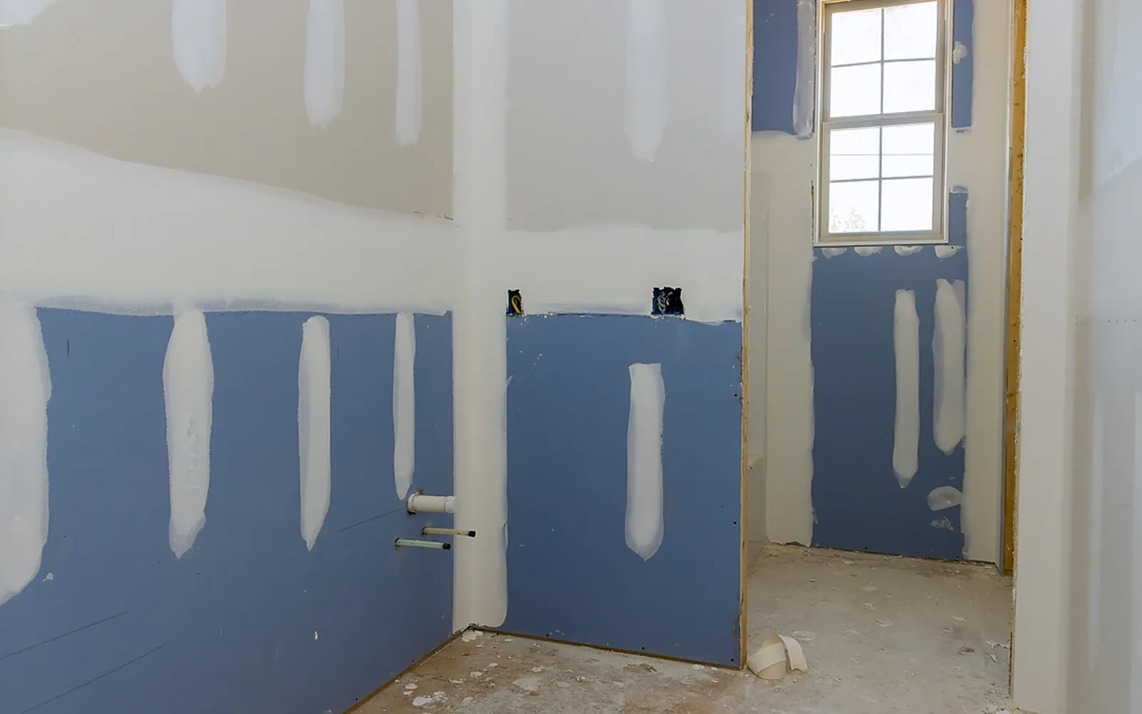 Blue moisture-resistant drywall hung in a bathroom with the joints first-coated