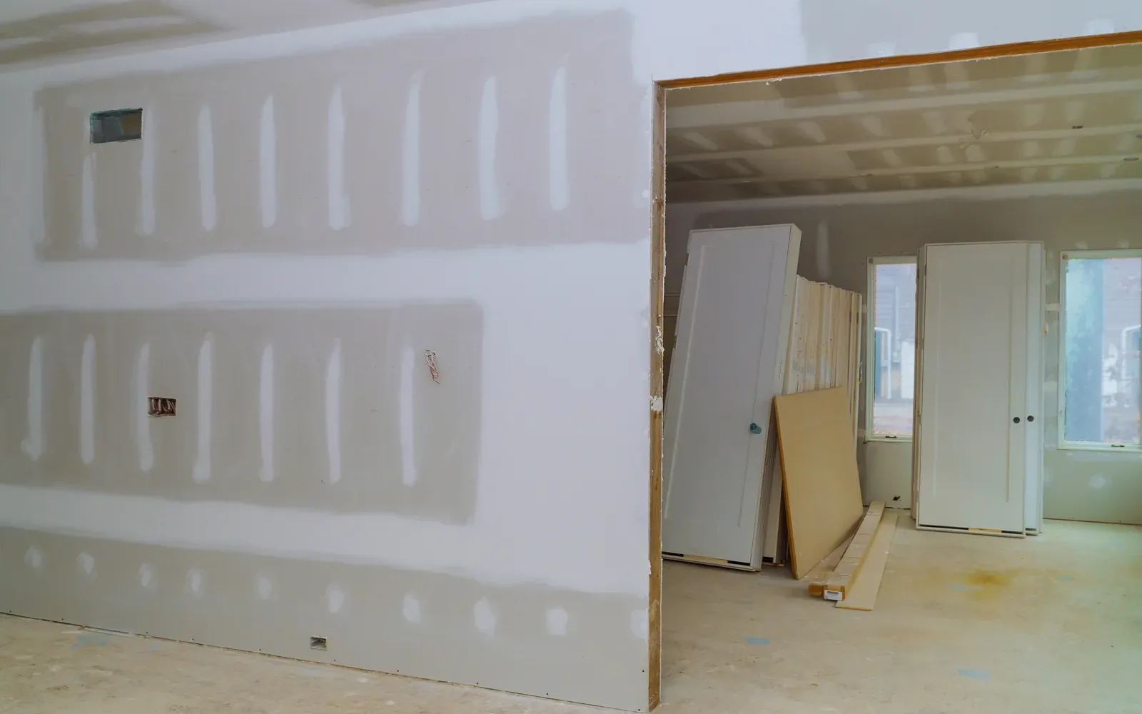 A room boarded out in drywall with an offcut panel leaning by the window