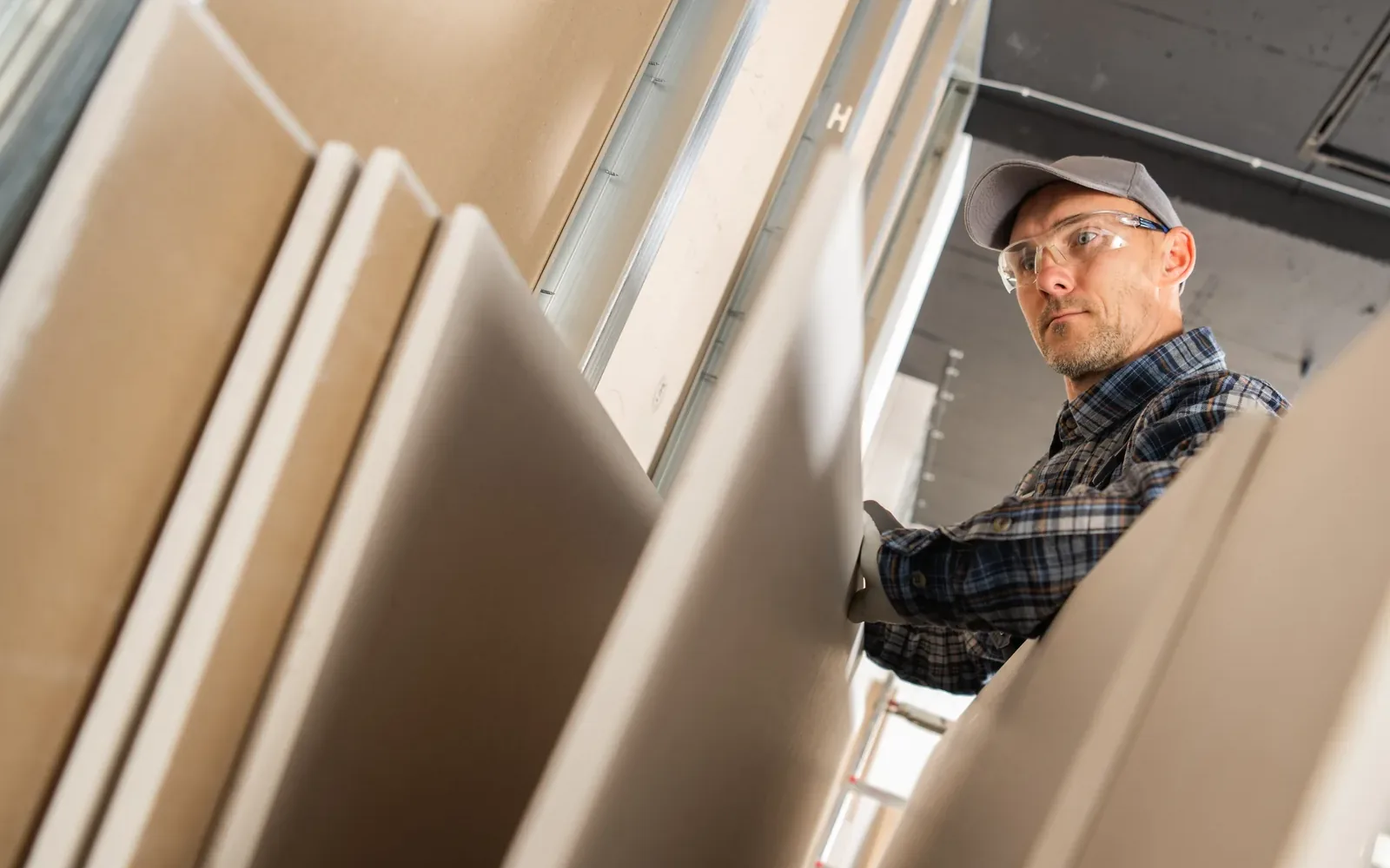 A worker looking over the drywall panels stacked where they were delivered to a site
