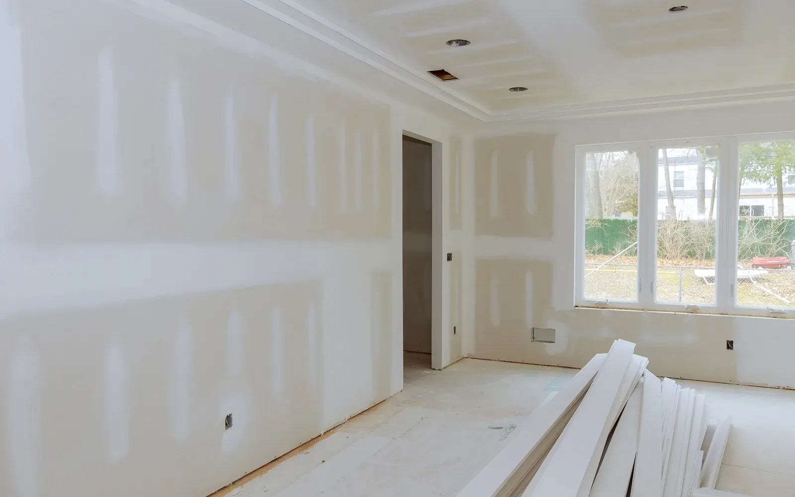 A large room boarded out in drywall with unused panels stacked flat on the floor