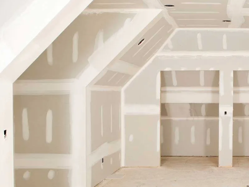 A boarded room under a sloping dormer ceiling with the angles taped