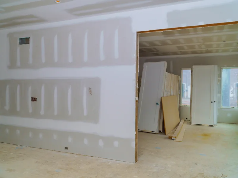 A boarded room with an offcut panel leaning by the window as the compound dries