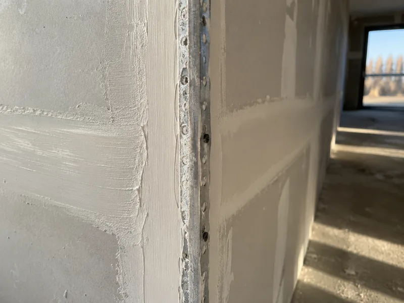 Metal corner bead fixed to an outside corner with the first coat of drywall compound feathered over it