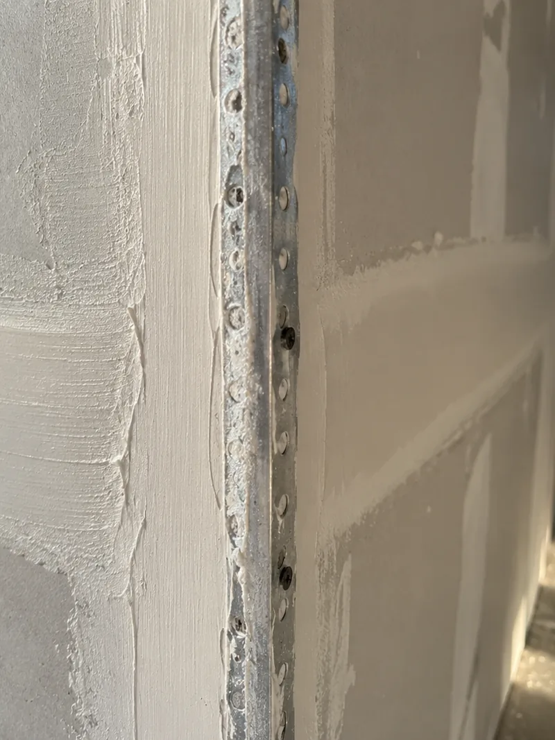 A finished outside corner, its metal bead feathered in with the first coat of compound