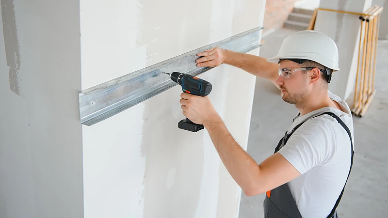 Light-gauge steel track fastened plumb for a new partition wall