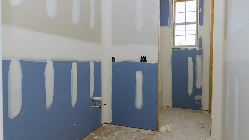 Moisture-resistant board on the wet-area walls of a bathroom remodel, with standard board above the splash line
