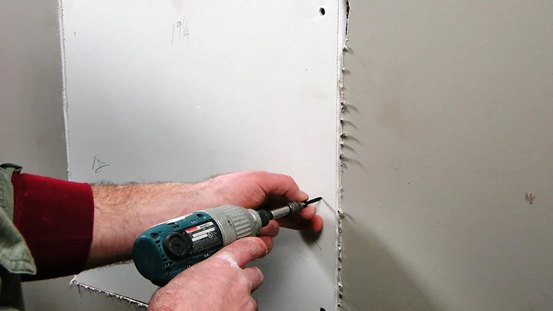 Driving screws to re-fasten drywall to the studs at a repair