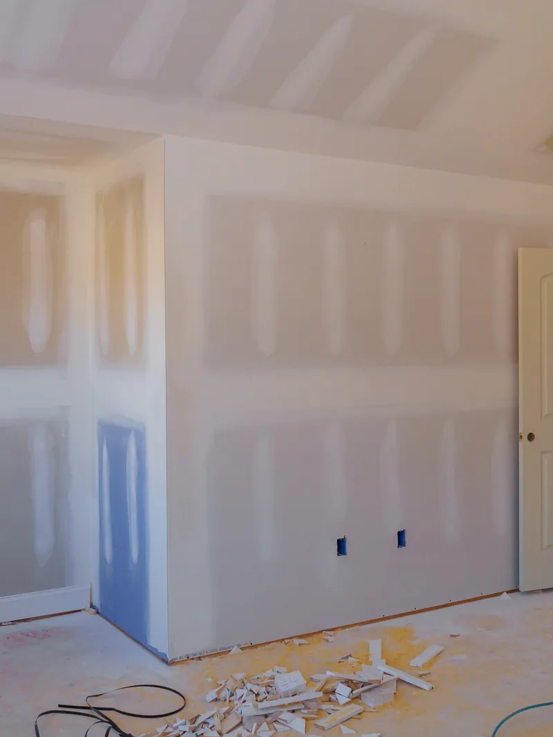 A part-renovated room with taped walls and a cabinet run going in against them