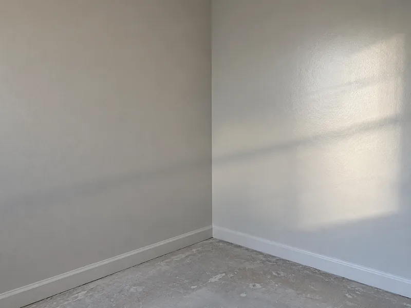 An inside corner where a flat matte wall meets one in a low sheen, the same colour reading differently in raking light