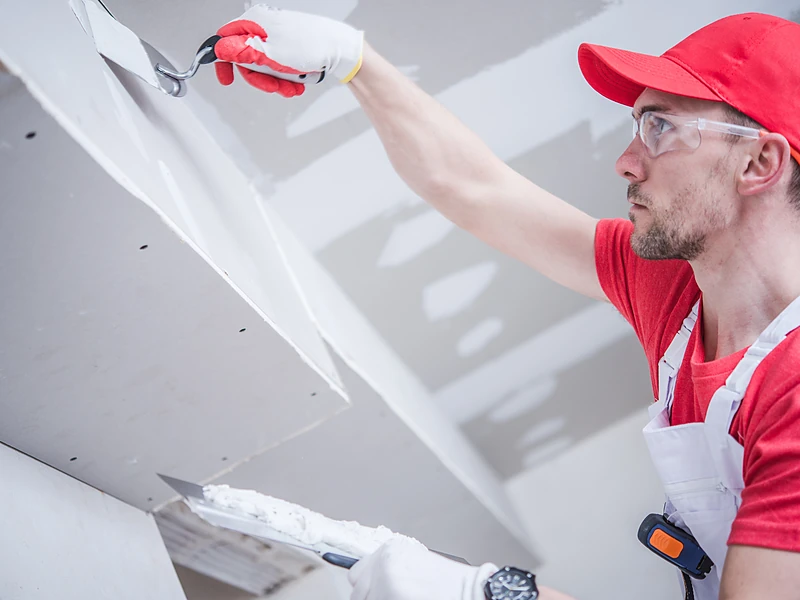 Drywall finisher smoothing a taped ceiling joint before texture matching