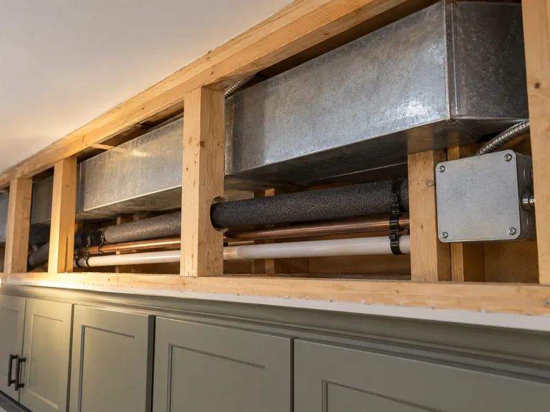 An opened soffit showing the duct, pipework and junction box it was built to hide