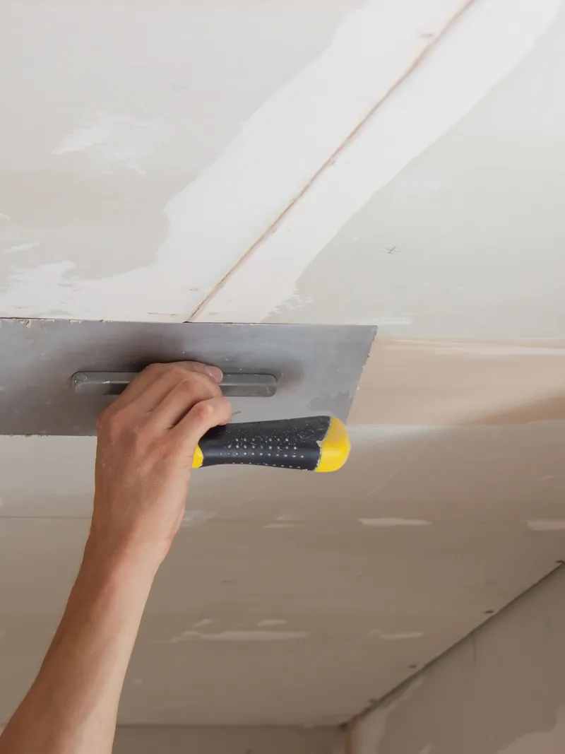 A trowel worked flat across a ceiling overhead, the surface left behind to live with